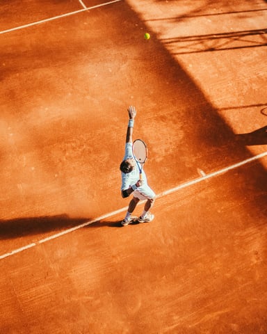 Player serving on clay tennis court